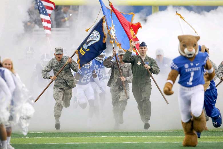 military students carrying flags onto football field