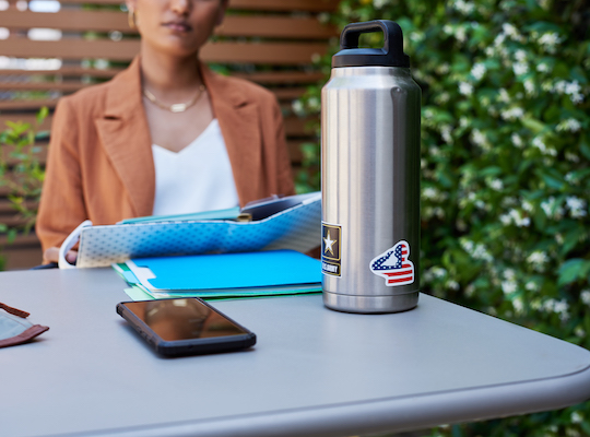 woman at table outside with US Army tumbler